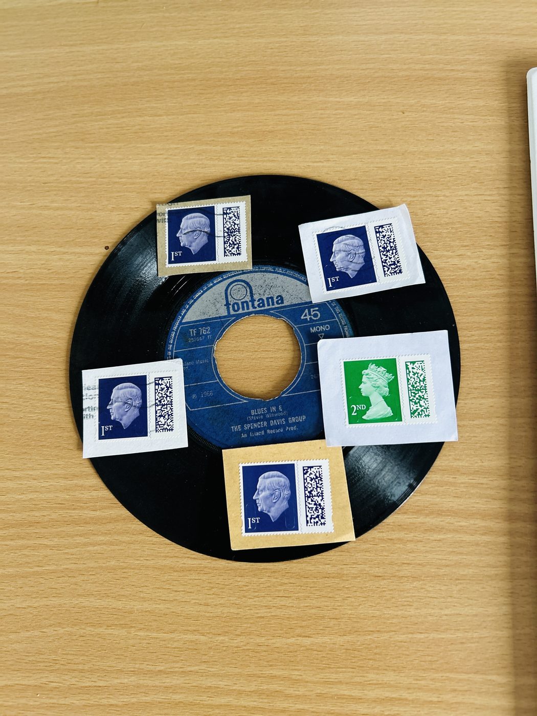 A small vinyl single with used first- and second-class postage stamps arranged around it